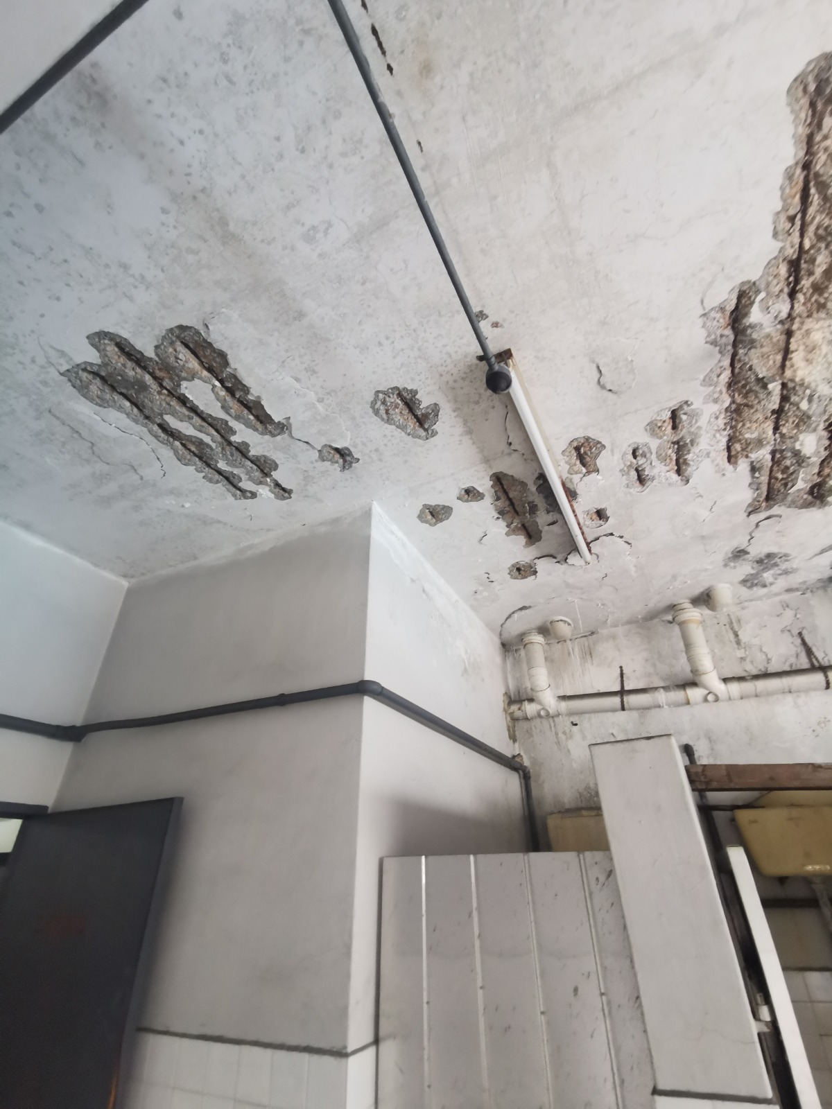 Spalling concrete repair in progress with damaged cover removed back to sound material