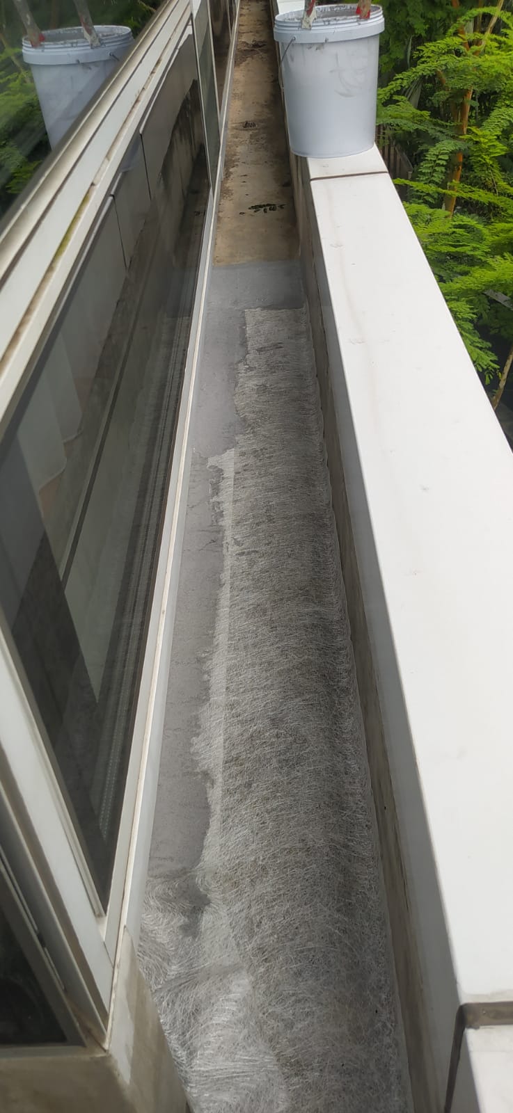 Reinforced concrete gutter being prepared and coated during waterproofing works